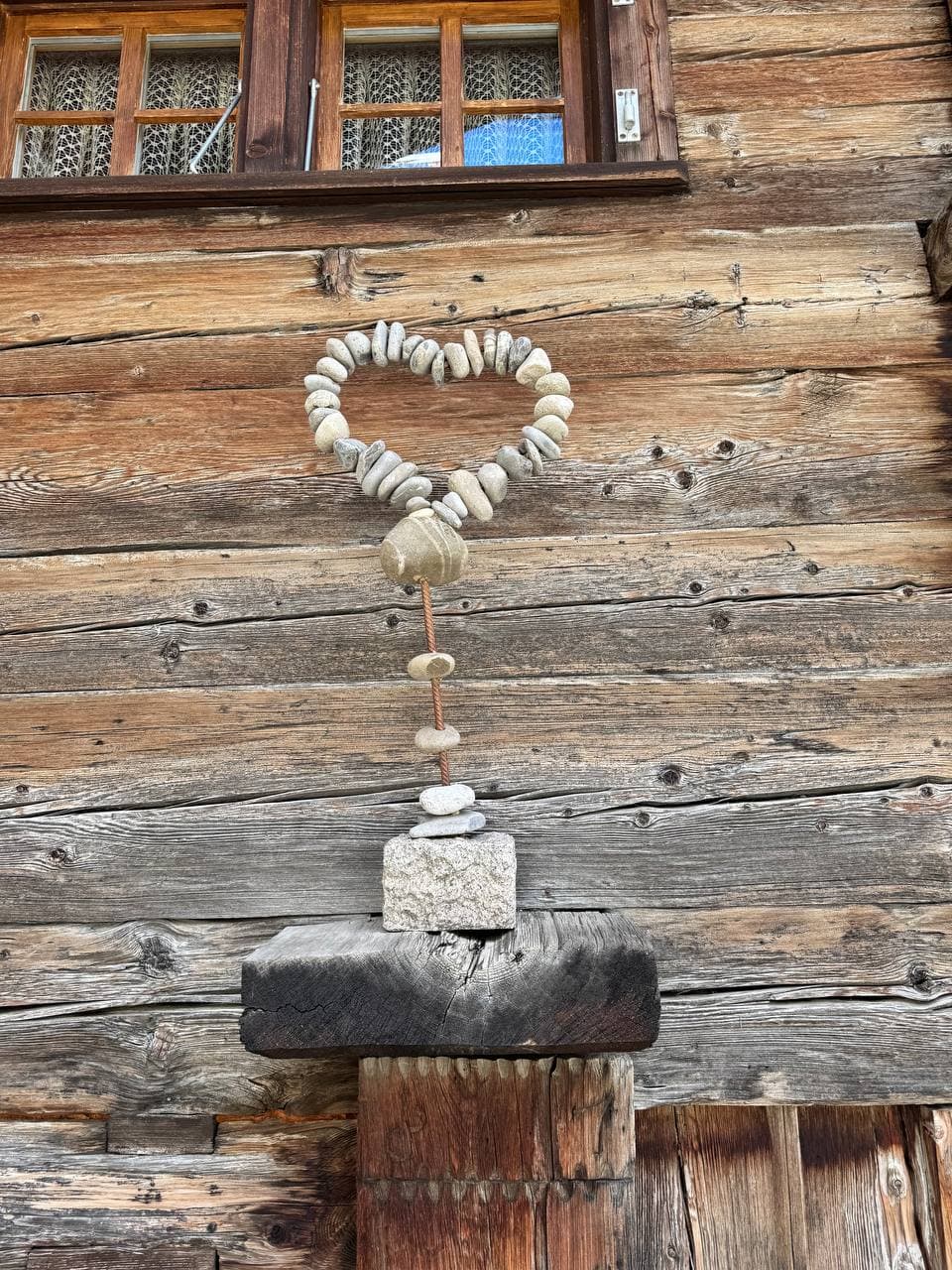 Herz aus Muscheln und Steinen an einer alten Holzwand